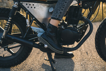 Close-up of biker girl's leg on motorcycle stand.