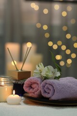 Obraz na płótnie Canvas Beautiful composition with different spa products and flowers on white towel against blurred lights
