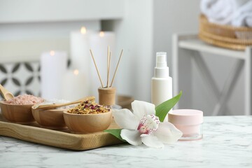 Fototapeta na wymiar Beautiful composition with different spa products and orchid flower on white marble table indoors