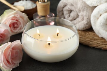 Spa composition with burning candle and rose flowers on grey table, closeup