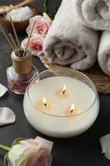 Spa composition with burning candle and towels on grey table