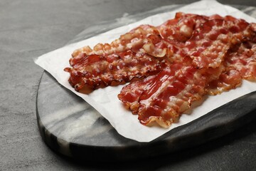 Fried bacon slices on dark table, closeup
