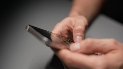 Close-up cropped shot of unrecognizable man using smartphone seated at desk indoors, sharing sms, messaging through messenger, mobile application usage for communication, spend leisure on internet