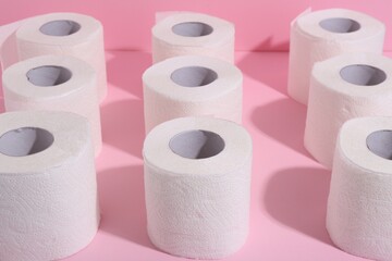 Many soft toilet paper rolls on pink background, closeup