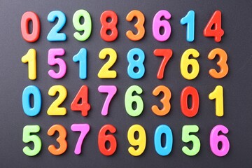 Colorful numbers on dark gray background, flat lay