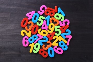 Colorful numbers on dark wooden school desk, top view