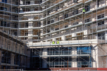 Workers on the line of a new building rest while sitting at height

