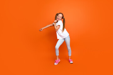 Full length photo of cheerful satisfied schoolchild have good mood dancing isolated on orange color...