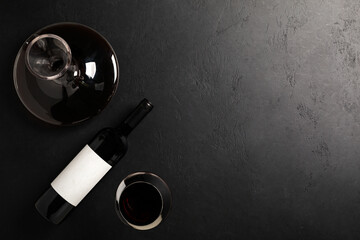Decanter, glass and bottle with red wine on black. Flat lay