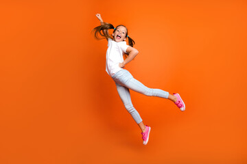 Full length profile photo of crazy schoolkid superhero raise fist flying jumping isolated on orange color background