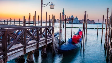 Fotobehang Gondels Serene Dawn over Venice with Gondola Blurring in Motion by Wooden Docks Moored by Saint Mark Square with San Giorgio di Maggiore Church in Background, Venice, Italy