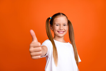 Photo portrait of cute little lady showing thumb up gesture dressed stylish striped garment isolated on orange color background
