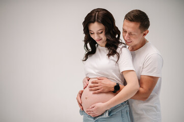 Family isolated on a white background. Pregnant woman and handsome man hugging tummy at home. Couple waiting for baby. Husband embraces belly wife. Nine months. Loving couple smiling embrace together.