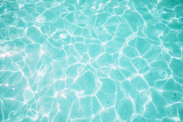 Background, blue water waves in the pool with sun reflection. Top view, selective focus
