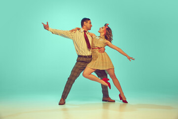 Beautiful woman and man looking at each other while dancing in motion against gradient mint background. Concept of art, hobby, music, fashion, love energy, happiness, mood, action.