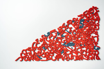 Top View image of a group of Arabic letters made of wood, colored red and blue on a white background