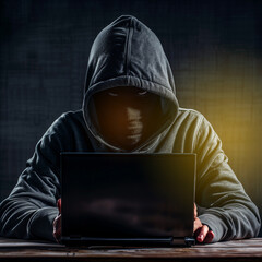 Hacker stealing data from laptop. Dark face. Blurred background.