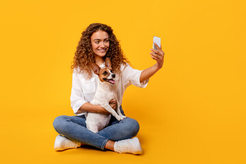 Curly-haired woman takes selfie with her joyful Jack Russell