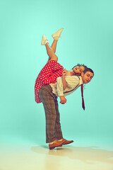 man and woman, talented dancers in retro style clothes dancing swing, boogie-woogie against gradient mint background. Actors in motion. Concept of music, energy, happiness, mood, action