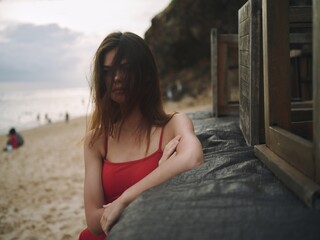 Young woman with a sad look looks into the camera with loose hair portrait on the beach on a trip...