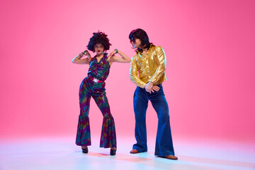 Talented dancers, man and woman in retro style outfits posing against gradient pink studio...