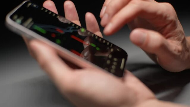 Close-up cropped shot of unrecognizable crypto trader holding smartphone and analyzes graph of growth of crypto stock market on stock exchange. Stock market data statistics using mobile app.