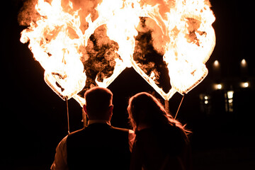 Fire show. The newlyweds look at the fiery hearts. Wedding, show program.