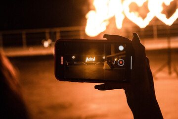 Fire show. The girl takes a video on her phone. Burning hearts.