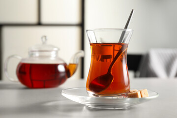 Traditional Turkish tea in glass and sugar cubes on white table, closeup. Space for text