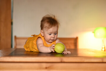 Fototapeta premium Small child with a green apple. The baby is lying on his stomach