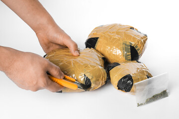 Smuggling and drug trafficking. Man opening package of narcotics with box cutter on white...