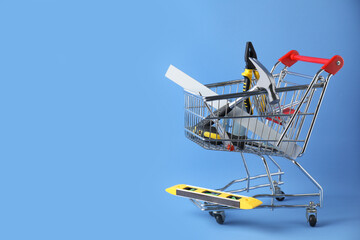 Small shopping cart with set of construction tools on light blue background. Space for text