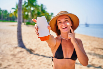 Portrait of satisfied young joyful happy smiling woman using facial spf sunscreen while sunbathing and relaxing in the sun. Sunburn protection and healthy skin