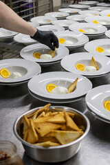 Chef di un ristorante da cerimonia mentre guarnisce i piatti in uscita del menù