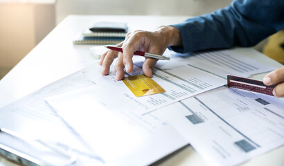 Asian businessman holding credit card to checking invoice and calculate cost from online order, A...
