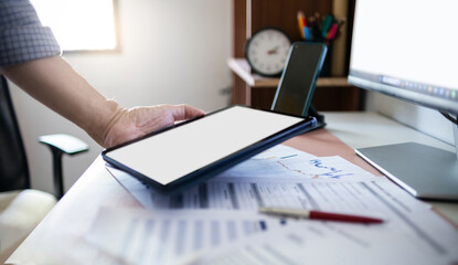 Businessman using tablet with desktop pc and documents chart to analyzing data of investment to...