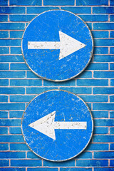 Old blue metallic arrow sign against an aged brick wall indicating to go left and right - concept...