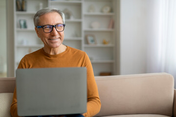 Curious retired man with computer on his lap, copy space