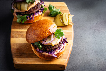 Beef burgers with pickles and red onion on cutting board, copy space - 740877506