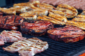 Roasted pork knuckle, chicken breast, and traditional Romanian mititei on the grill, focus on pork knuckle