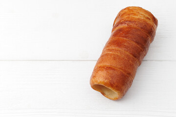 Traditional Hungarian donuts (Kürtöskalács), commonly known as chimney cake, on a white wooden background from above view, with selective focus.