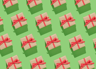 Pattern of brown gift boxes on with red bows on green background.