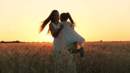 Happy family mother and daughter silhouette playing with love rotation at sunset sunrise wheat...