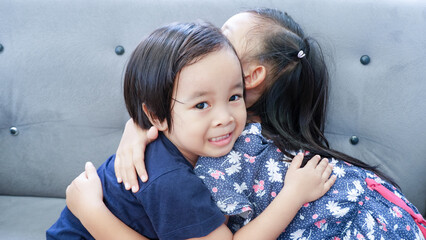 Portrait of togetherness Asian child hugging little brothers on couch.