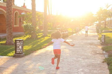 A child runs towards the sun's rays along the road. Sunset running. Sunlight. freedom of choice