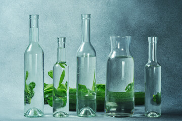 Glass water bottles and fresh green zucchini on a textured gray surface