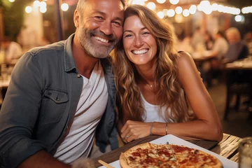 Foto op Plexiglas Happy adult cute couple have fun eating a pizza together outdoor in traditional italian pizzeria restaurant sitting and talking and laughing. People enjoying food and travel lifestyle. Tourism © simona