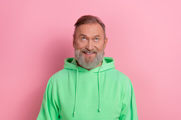 Obraz premium Photo of cheerful positive guy dressed green hoodie looking up empty space isolated pink color background
