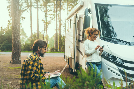 Adult couple of traveler enjoy outdoors leisure activity together outside a modern motorhome camper van parking in the forest. Freedom and remote work concept vanlife lifestyle. Parking destination