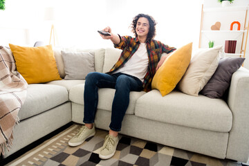 Full length photo of positive good mood guy dressed checkered shirt watching tv changing program...